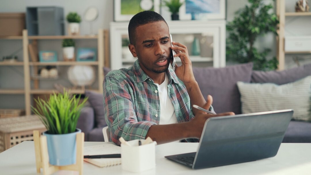 Brazilian man having a calm video call conversation at a wooden desk